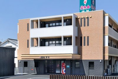 介護施設の建物外観。3階建てのレンガ造り、白いバルコニーが特徴的な施設の正面